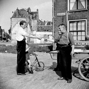 823265 Afbeelding van Piet Schoonhoven (rechts; bijnaam: Piet 't Joodje ) en een klant bij zijn vis- en zuurkar in de ...